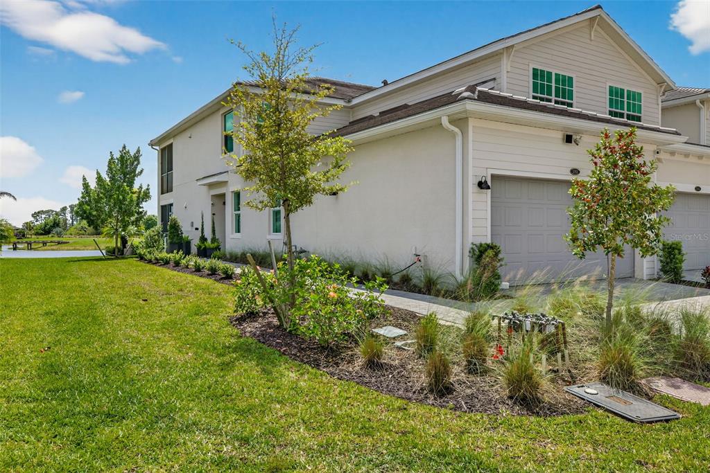 A two-story house with a beige exterior, a gray garage door, and a grassy yard — 43250 WATER BIRD WAY UNIT 5911, PUNTA GORDA, FL