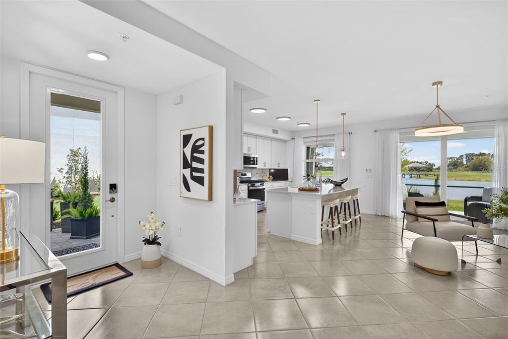 An open-concept kitchen and living area features tile flooring, a center island, and glass doors — 43250 WATER BIRD WAY UNIT 5911, PUNTA GORDA, FL