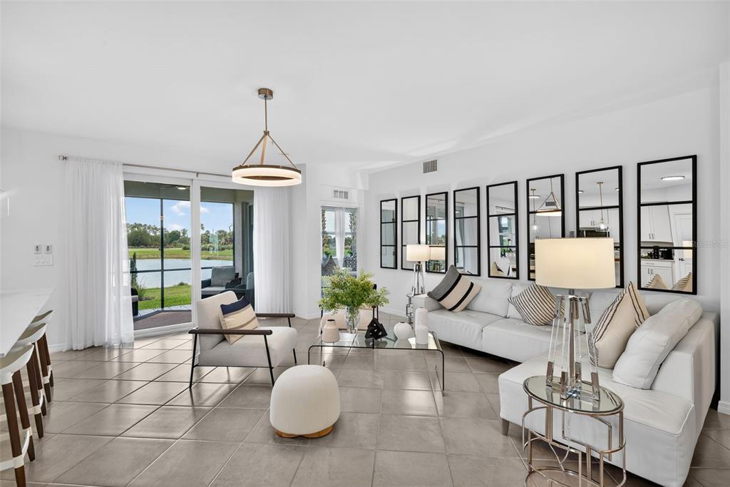 A bright living room features tile floors, a white sofa, and large wall-mounted mirrors — 43250 WATER BIRD WAY UNIT 5911, PUNTA GORDA, FL