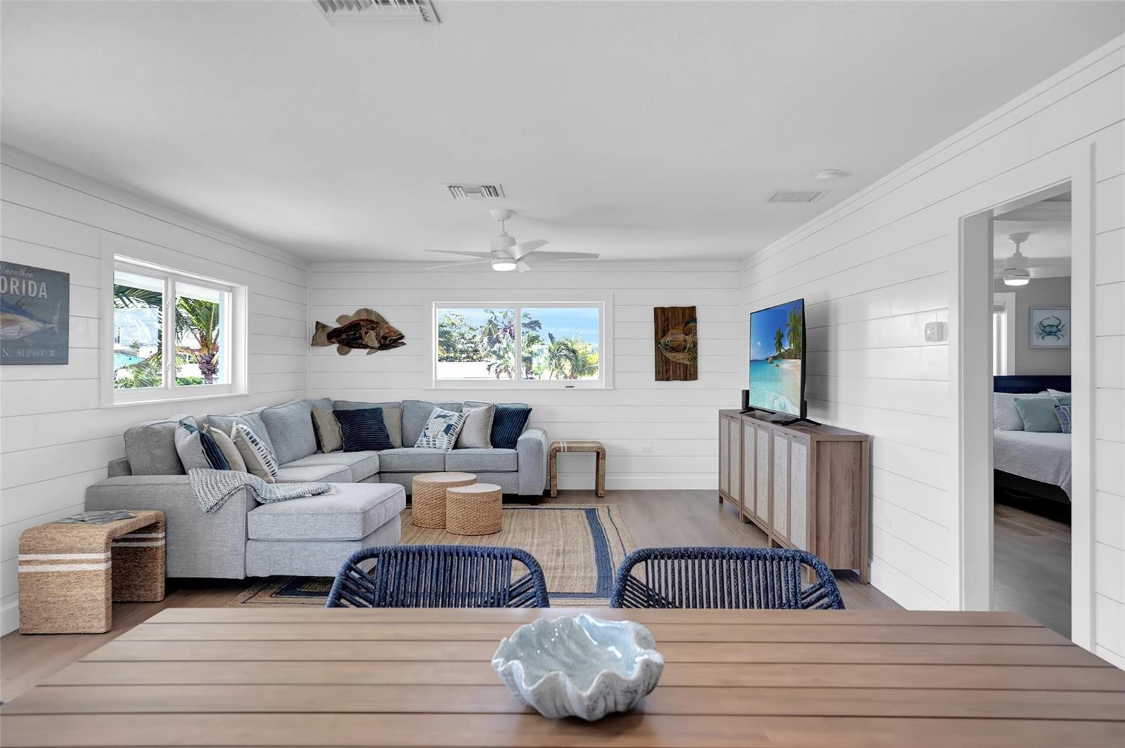 A living room with white shiplap walls, a grey sectional sofa, and a television console — 10999 Ave 3rd Avenue, Marathon FL 33050, MARATHON, FL