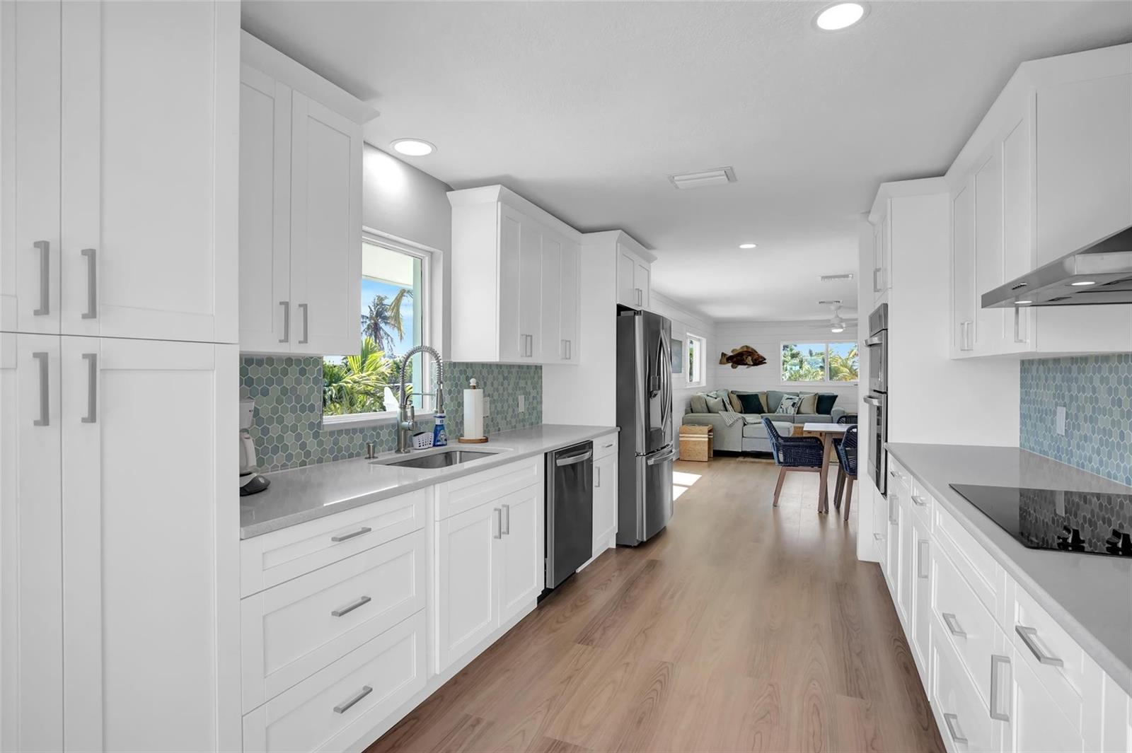 A modern kitchen features white cabinetry, light countertops, a blue hexagonal backsplash, and stainless appliances — 10999 Ave 3rd Avenue, Marathon FL 33050, MARATHON, FL