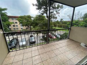 A screened-in balcony with tiled flooring overlooks a parking lot and surrounding trees — 4166 Inverrary Drive # 303, Lauderhill FL 33319, LAUDERHILL, FL