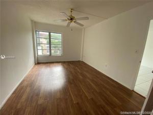 An empty room with wood-look flooring, a ceiling fan, and a window overlooking the exterior — 4166 Inverrary Drive # 303, Lauderhill FL 33319, LAUDERHILL, FL