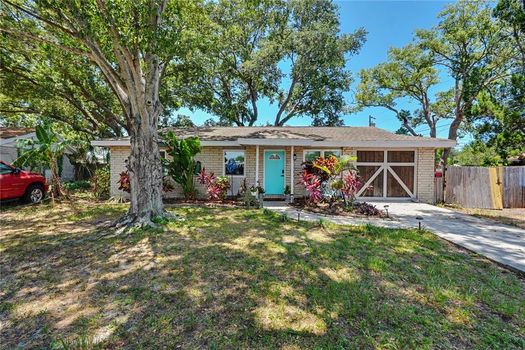 A single-story brick house with a bright blue front door and a large tree — 11208 DUNCAN STREET, SEMINOLE, FL