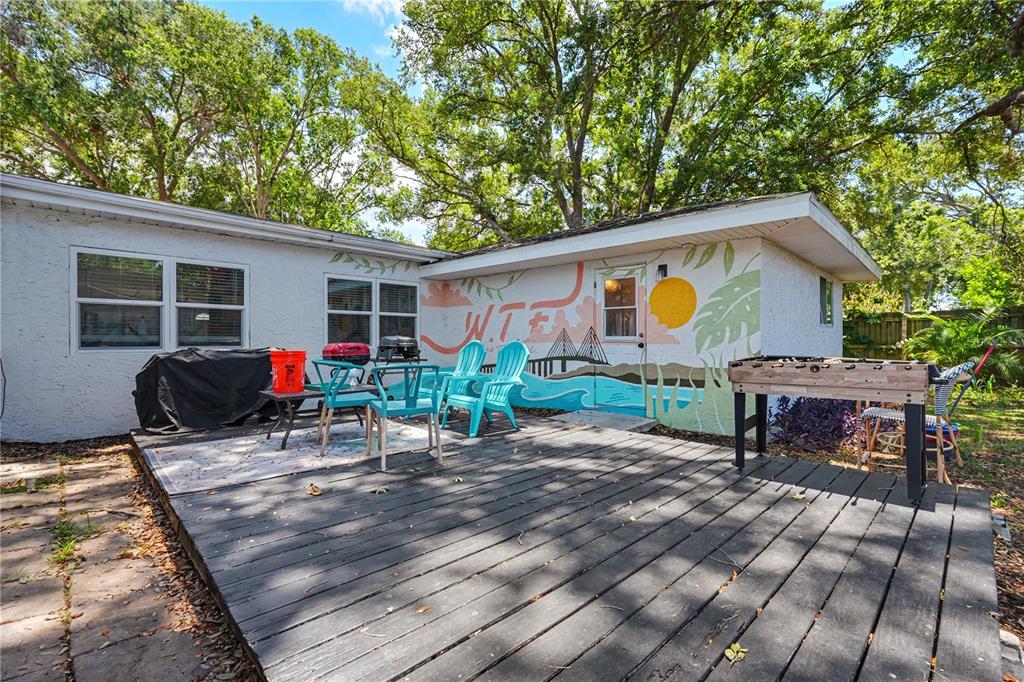 A backyard deck features a mural, outdoor seating, and a foosball table near a house — 11208 DUNCAN STREET, SEMINOLE, FL