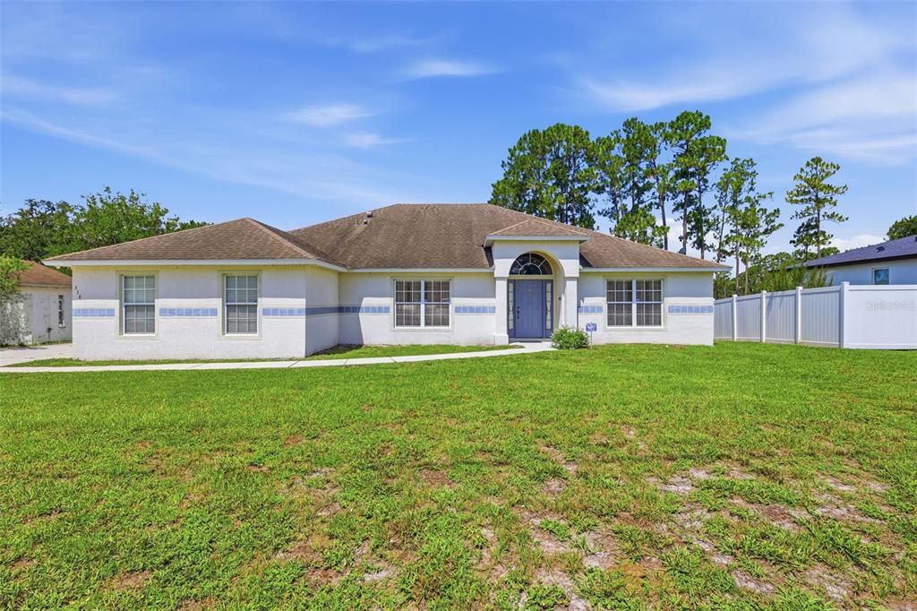 A single-story house with a white stucco exterior, blue trim, and a brown shingled roof — 516 GLEN HAVEN DRIVE, DELTONA, FL