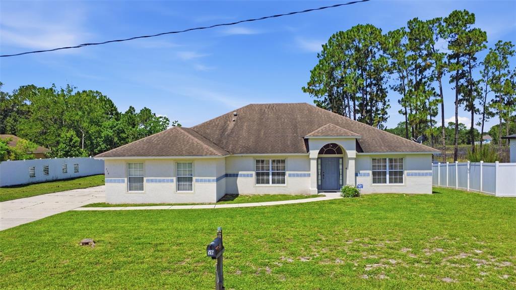 A single-story house with a beige stucco exterior, a brown roof, and a front walkway — 516 GLEN HAVEN DRIVE, DELTONA, FL