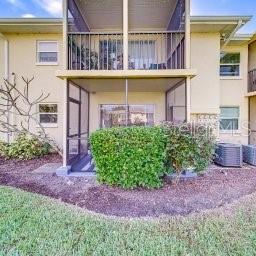 A two-story apartment building features screened-in balconies and a small bush in the foreground — 13125 WILCOX ROAD UNIT 5104, LARGO, FL