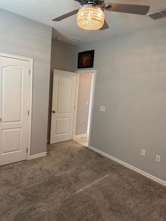 A bedroom with gray walls, carpeted flooring, a ceiling fan, and two white interior doors — 920 BOXELDER AVENUE, MINNEOLA, FL