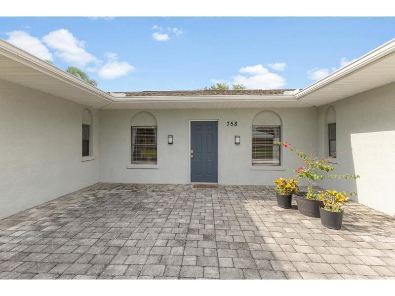 A paved courtyard leads to a blue front door flanked by two arched windows — 758 Beard Avenue, Sebastian FL 32958, SEBASTIAN, FL