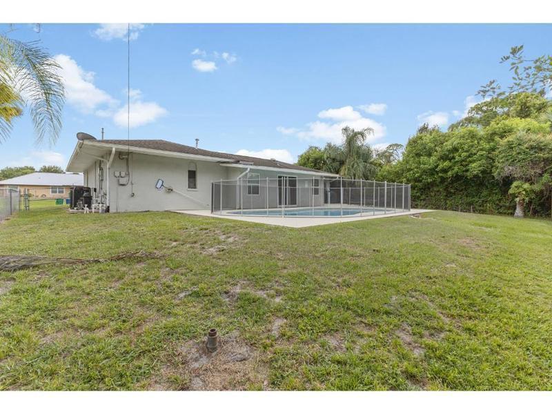 A backyard view of a house with a swimming pool enclosed by a safety fence — 758 Beard Avenue, Sebastian FL 32958, SEBASTIAN, FL