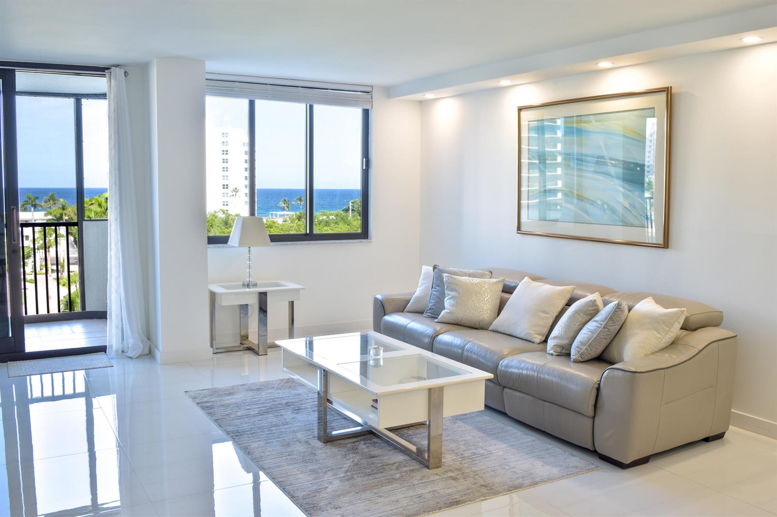 A living room with a leather sofa, glass coffee table, and ocean view through windows — 3420 S Ocean Boulevard # 7o, Highland Beach FL 33487, HIGHLAND BEACH, FL