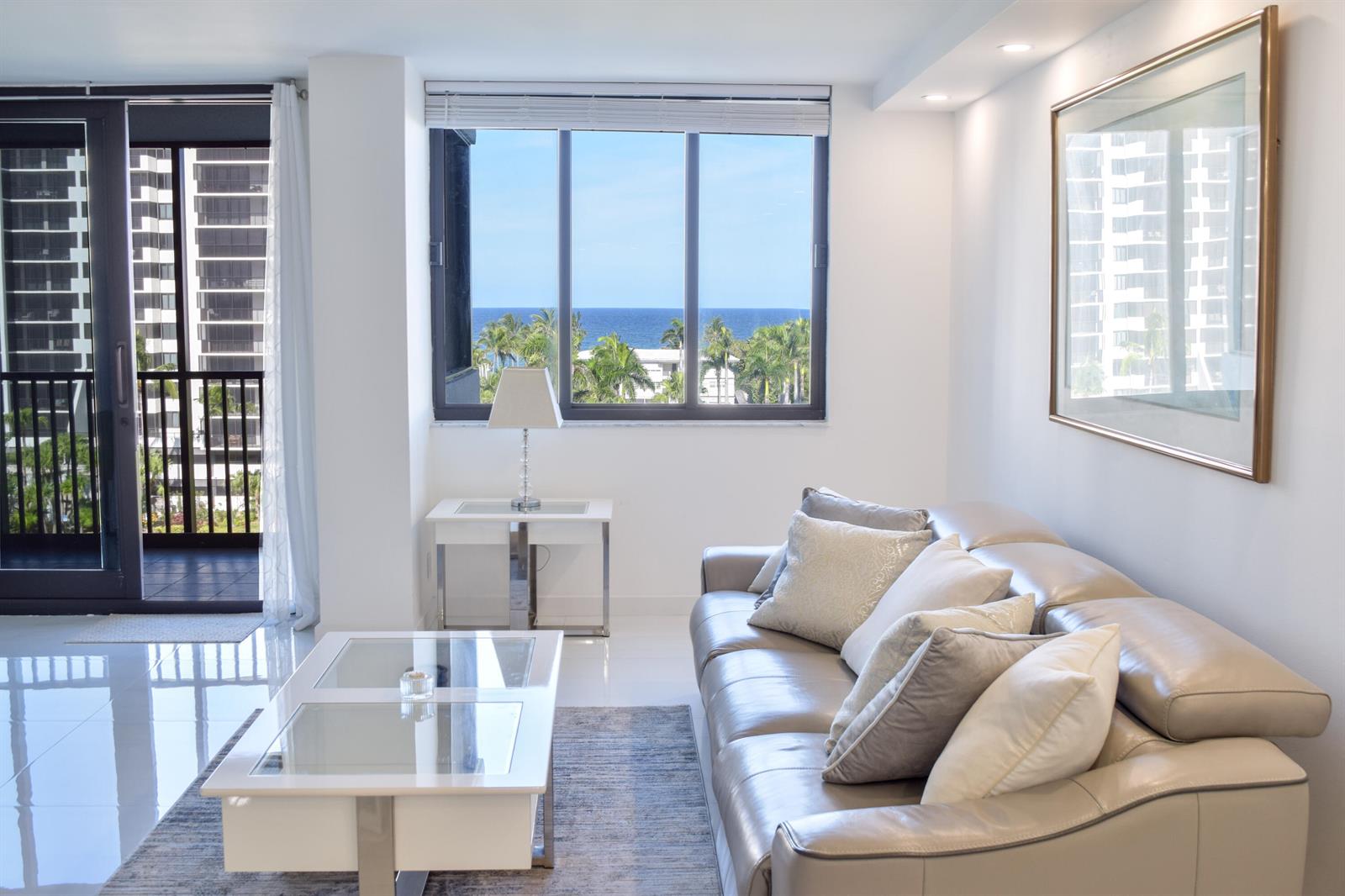 A living room with a leather sofa, glass coffee table, and a view of the ocean — 3420 S Ocean Boulevard # 7o, Highland Beach FL 33487, HIGHLAND BEACH, FL