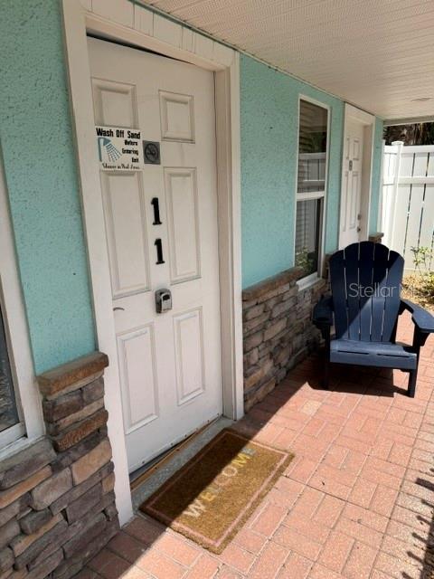 A white door labeled 11 sits on a brick patio next to a blue chair — 301 CENTRAL AVENUE S Unit 11, FLAGLER BEACH, FL