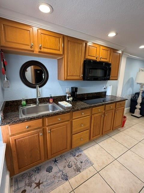 A kitchen features wood cabinets, granite countertops, a stainless steel sink, and a microwave — 301 CENTRAL AVENUE S Unit 11, FLAGLER BEACH, FL