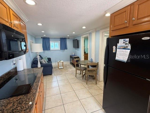 A kitchen with dark granite countertops opens into a living area with blue furniture — 301 CENTRAL AVENUE S Unit 11, FLAGLER BEACH, FL