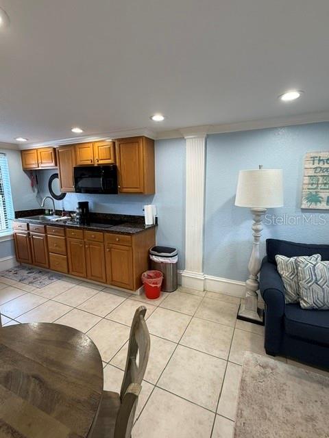 A kitchen with wood cabinets and tile floors sits next to a living area — 301 CENTRAL AVENUE S Unit 11, FLAGLER BEACH, FL