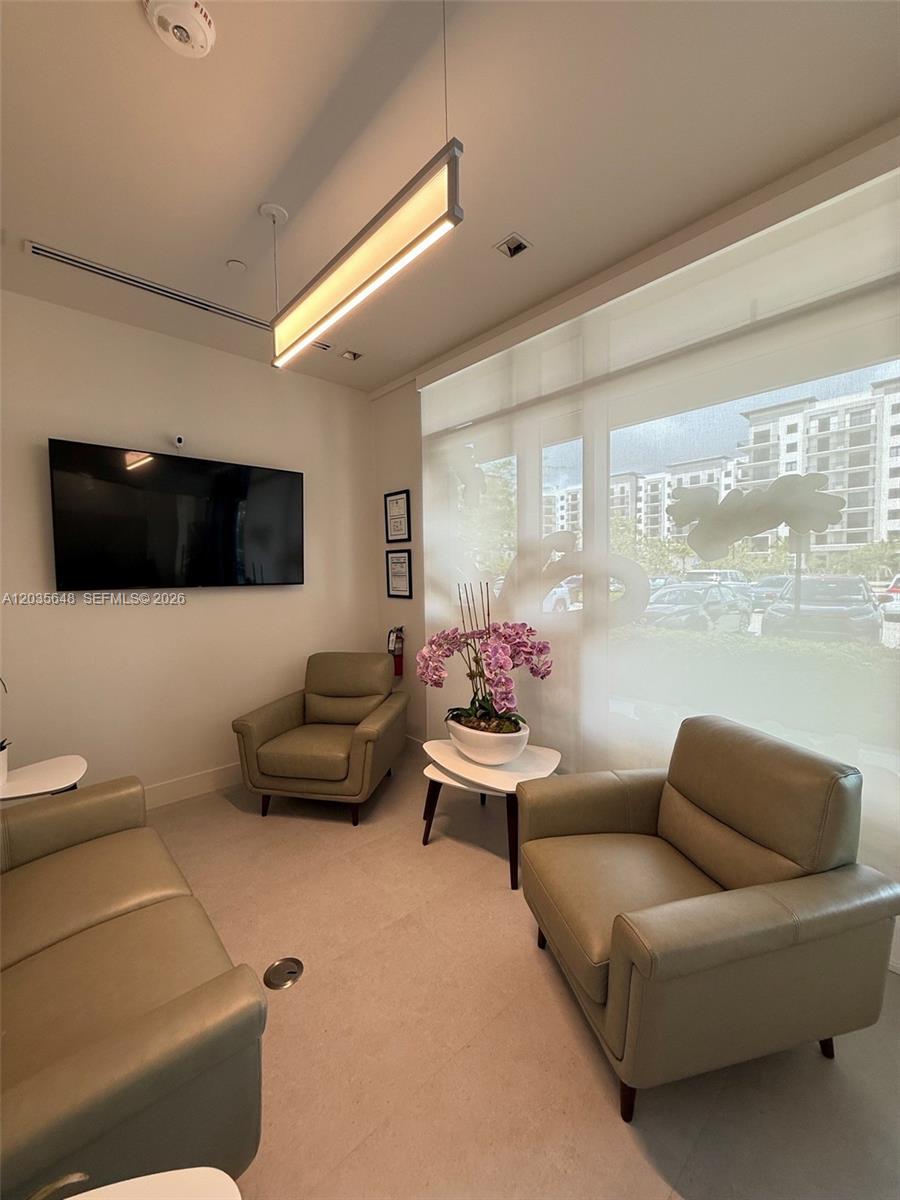 A waiting room features two leather armchairs, a side table with orchids, and a television — SWEETWATER, FL