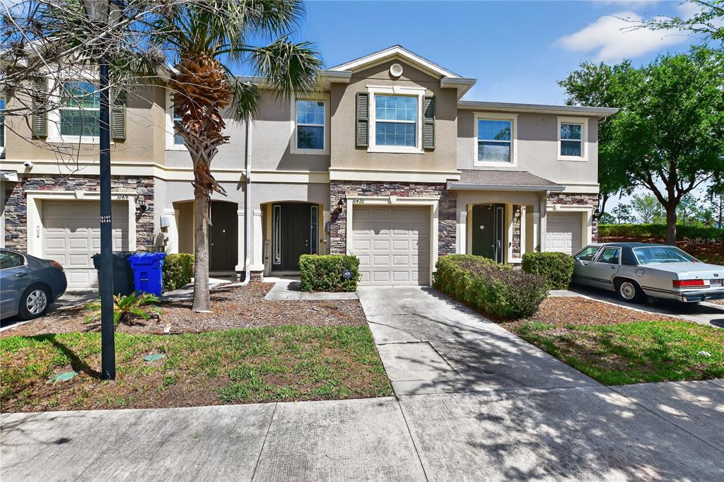 A row of attached townhomes with garages, stone accents, and a palm tree in front — 10420 BUTTERFLY WING COURT, RIVERVIEW, FL