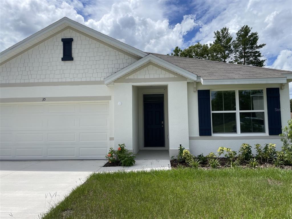 A single-story house with a white stucco exterior, blue shutters, and a two-car garage — 35 HICKORY COURSE TRAIL, OCALA, FL