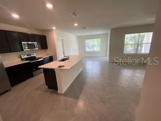 A kitchen with dark cabinets and a white island opens into a spacious living area — 35 HICKORY COURSE TRAIL, OCALA, FL