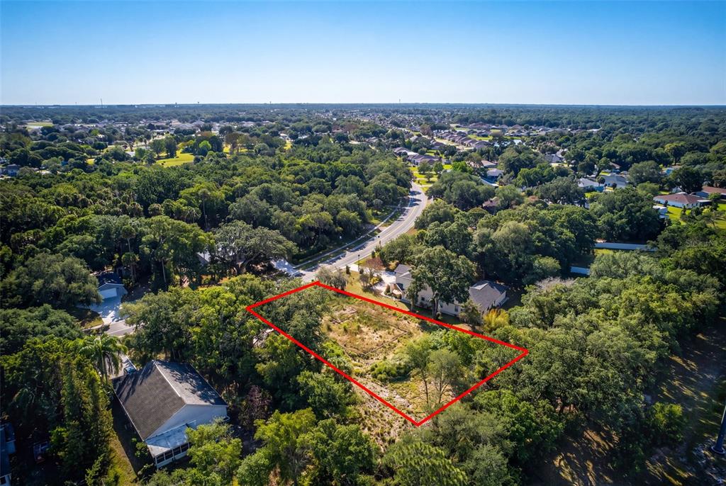 An aerial view shows a vacant, rectangular lot outlined in red surrounded by trees — 750 RIVIERA DRIVE NE, PALM BAY, FL