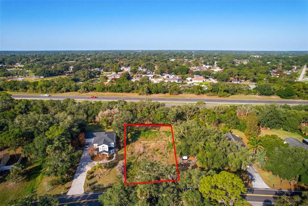 An aerial view shows a vacant rectangular lot outlined in red between two residential properties — 750 RIVIERA DRIVE NE, PALM BAY, FL