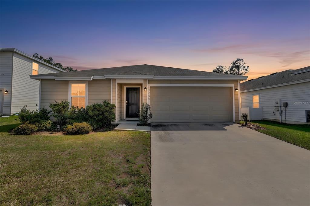 A single-story house with beige siding, a two-car garage, and a concrete driveway — 17499 NW 172ND AVENUE, ALACHUA, FL