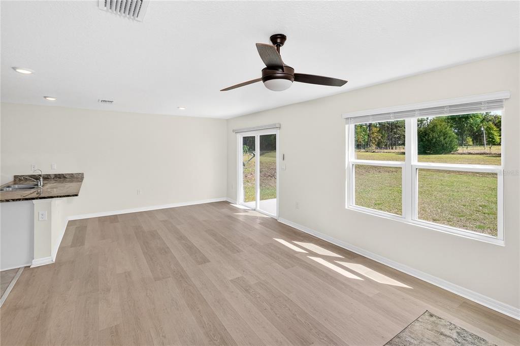 A bright living area features light wood-look flooring, a ceiling fan, and sliding glass doors — 17499 NW 172ND AVENUE, ALACHUA, FL