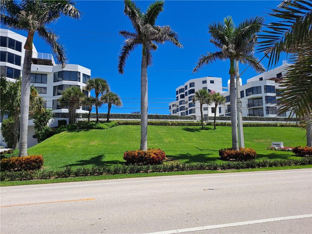 A grassy hill with palm trees sits in front of white multi-story apartment buildings — 2565 S Ocean Boulevard # 201n, Highland Beach FL 33487, HIGHLAND BEACH, FL