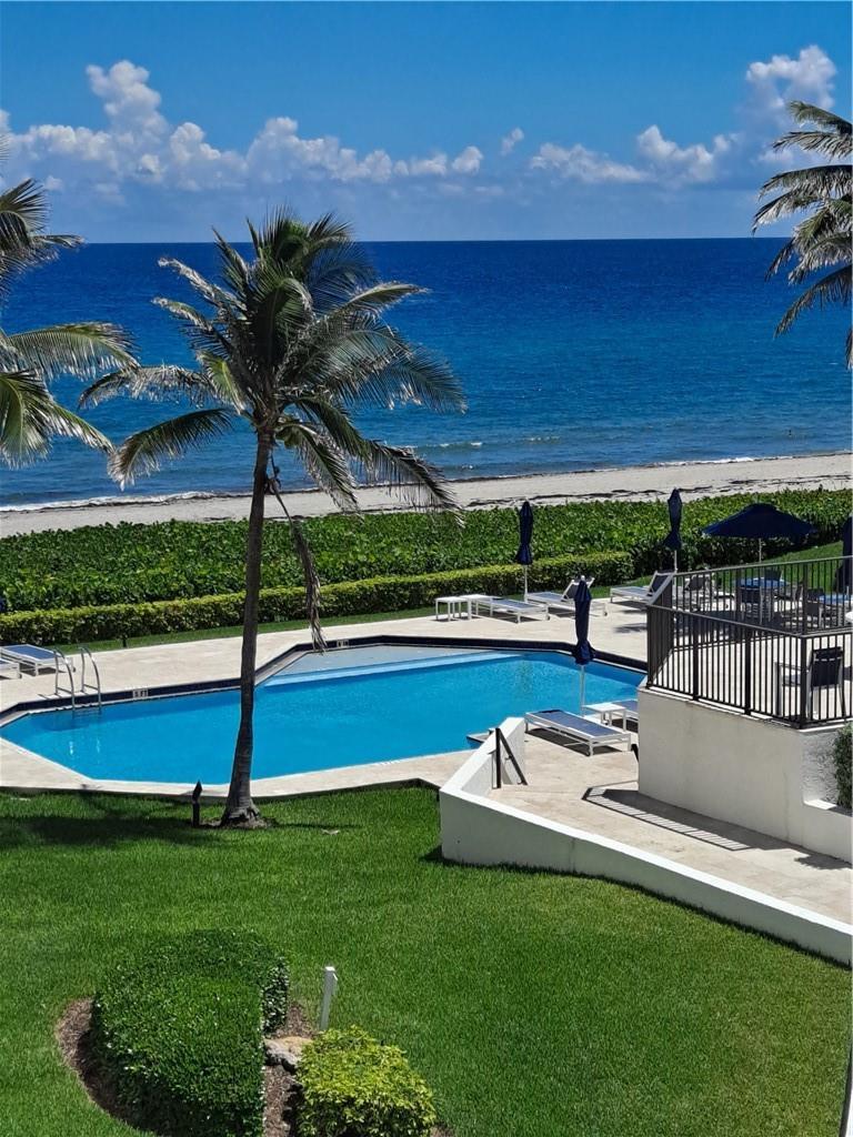 An outdoor swimming pool overlooks a sandy beach and the ocean with palm trees nearby — 2565 S Ocean Boulevard # 201n, Highland Beach FL 33487, HIGHLAND BEACH, FL