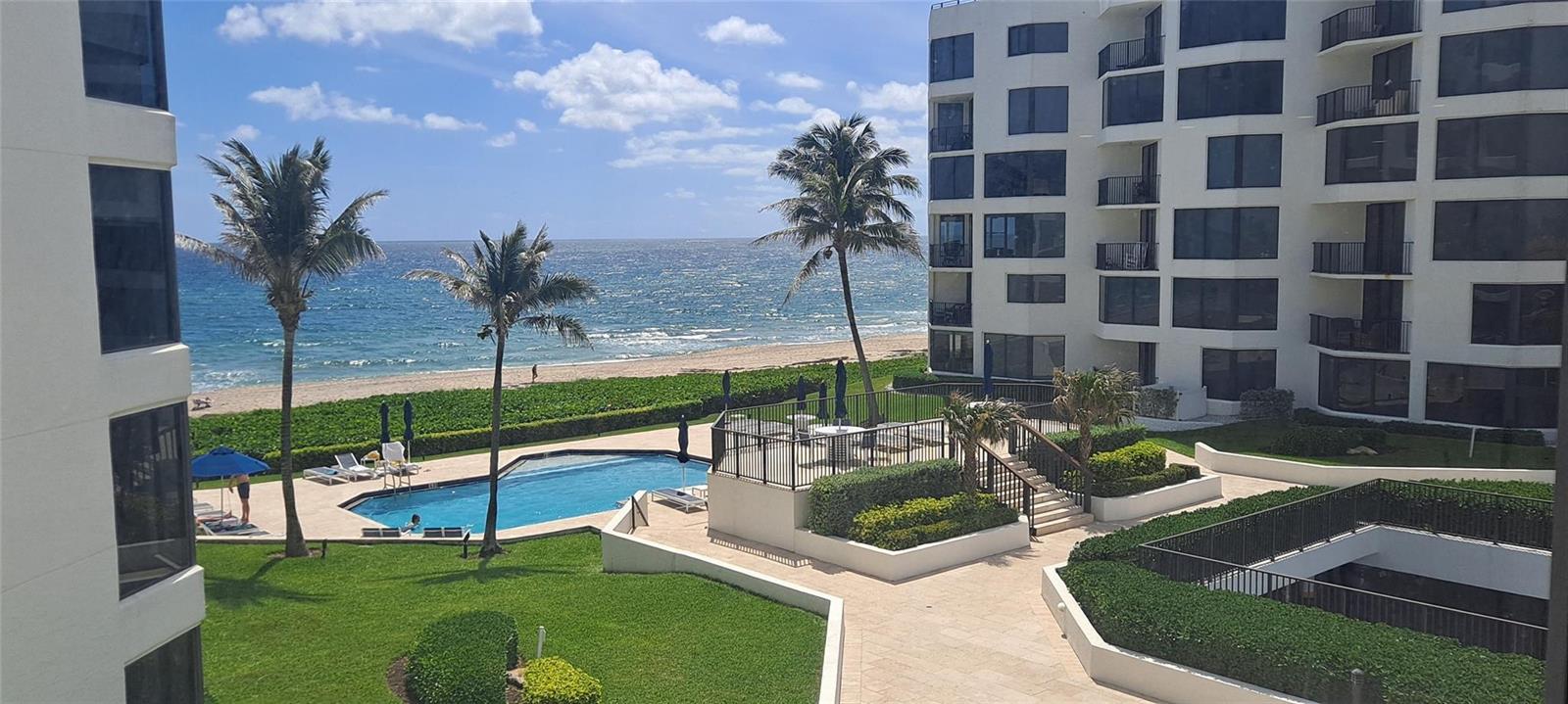 An elevated view of a beachside swimming pool, landscaped lawn, and multi-story residential building — 2565 S Ocean Boulevard # 201n, Highland Beach FL 33487, HIGHLAND BEACH, FL