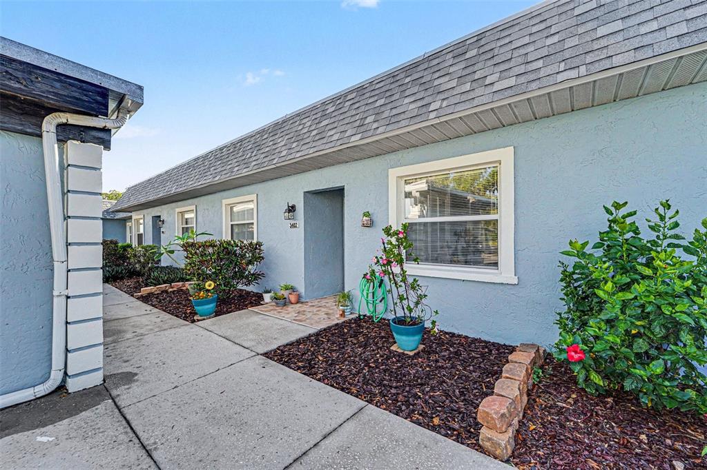 A blue exterior wall of a single-story building features a walkway, windows, and landscaping — 3402 TEESIDE DRIVE, NEW PORT RICHEY, FL