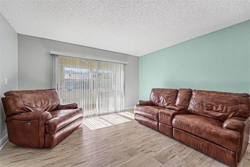 A living room features light wood-look flooring, a sliding glass door, and two brown sofas — 3402 TEESIDE DRIVE, NEW PORT RICHEY, FL