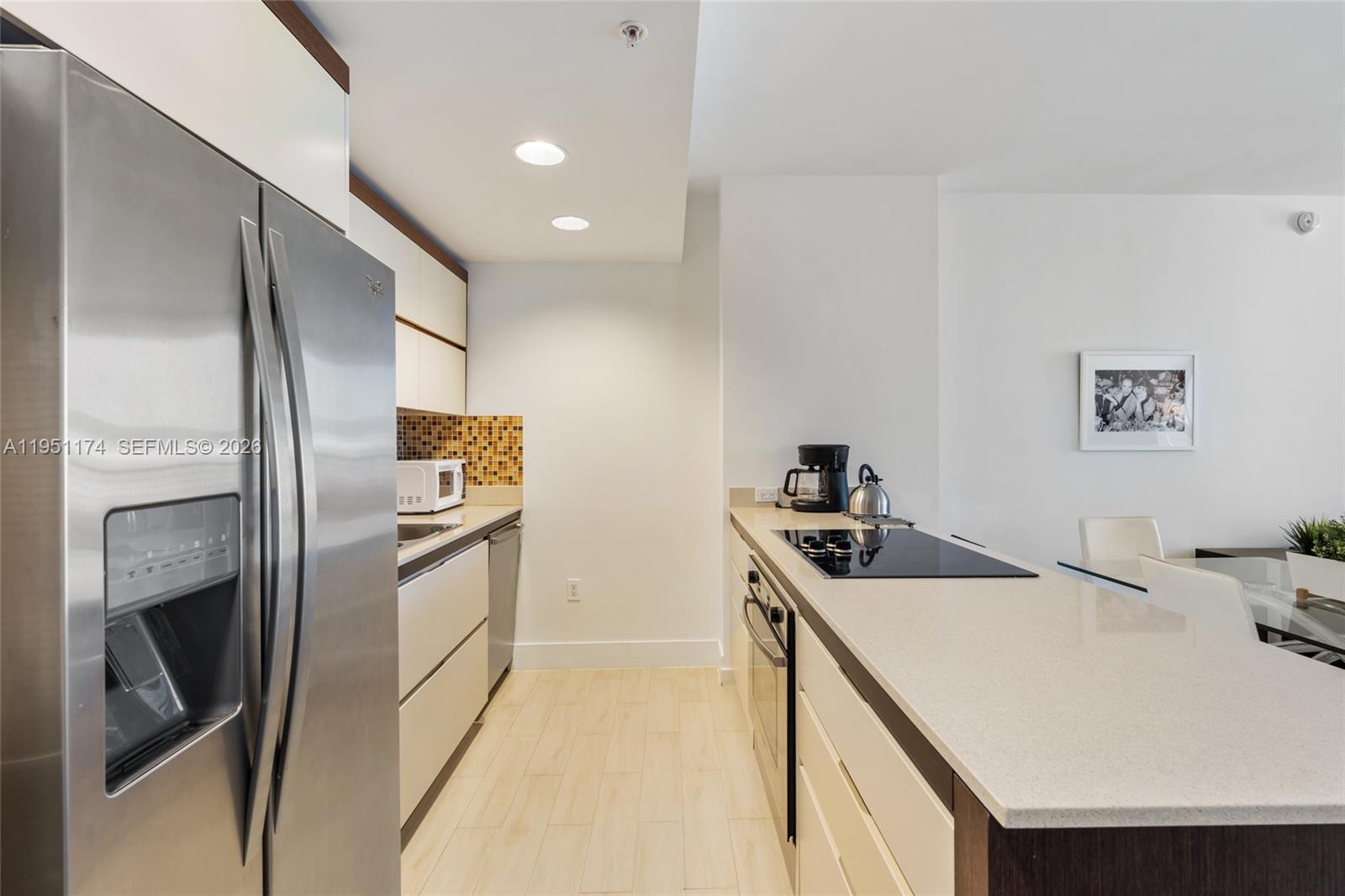 A living room features a blue sectional sofa, white coffee table, and balcony access — 2155 Washington Ct # 401, Miami Beach FL 33139, MIAMI BEACH, FL