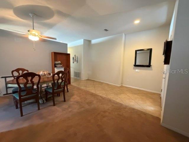 A dining area with a wooden table and chairs sits on carpeted flooring near tile — 409 SEA HOLLY DRIVE, BROOKSVILLE, FL