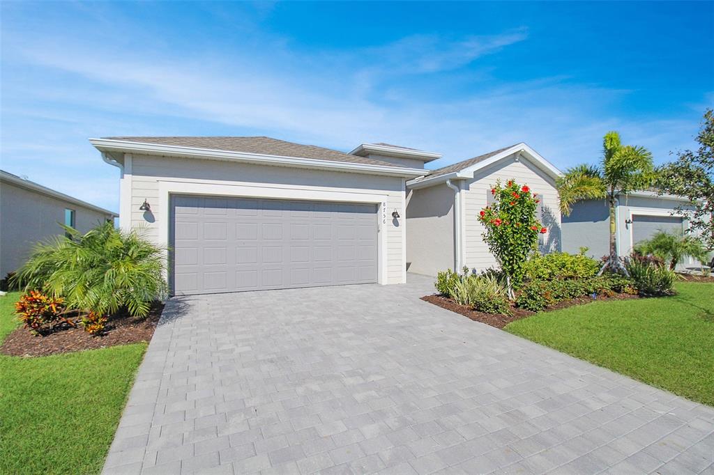 A single-story house with a gray garage door, paved driveway, and landscaped front yard — 8756 COCO BAY BOULEVARD, ENGLEWOOD, FL