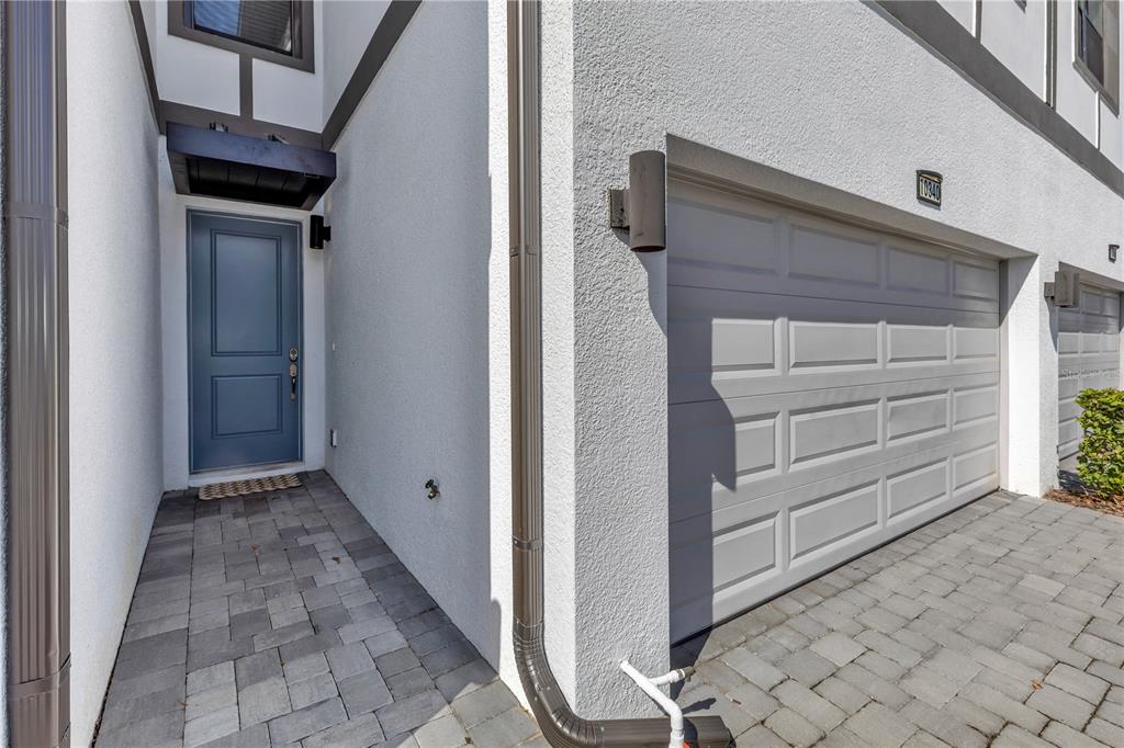 A blue front door sits beside a white garage door on a paved driveway — 10340 EBB TIDE LANE, ORLANDO, FL
