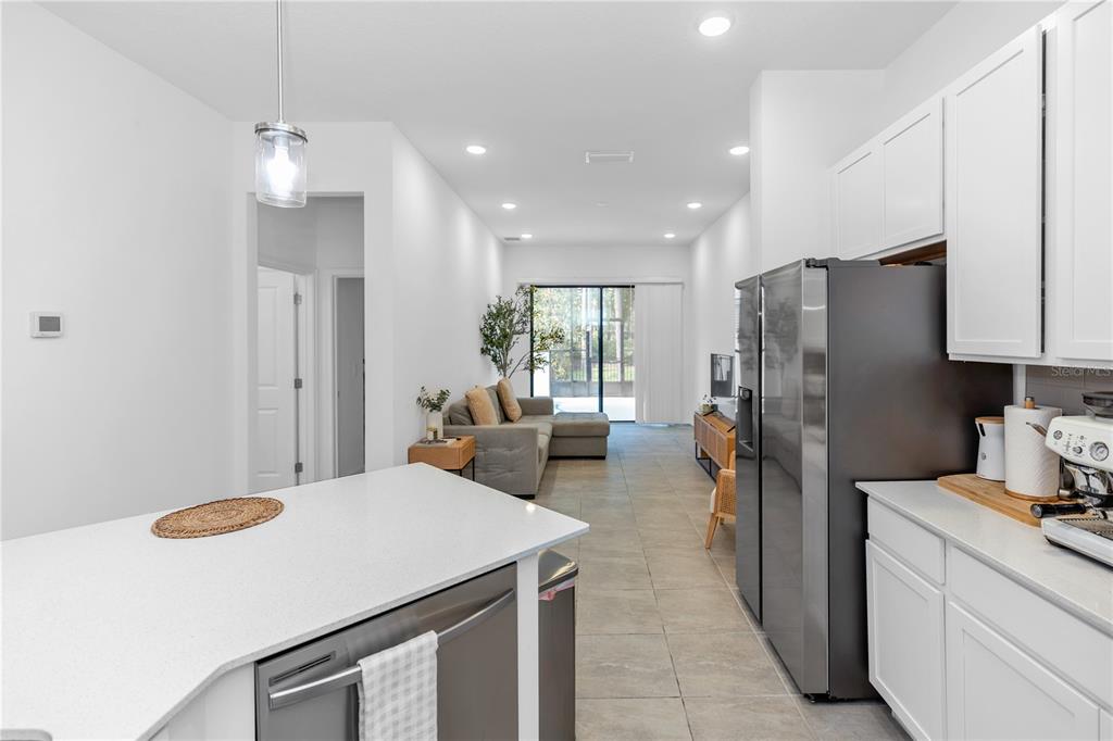 A modern kitchen with white cabinets and stainless steel appliances overlooks a living area — 10340 EBB TIDE LANE, ORLANDO, FL