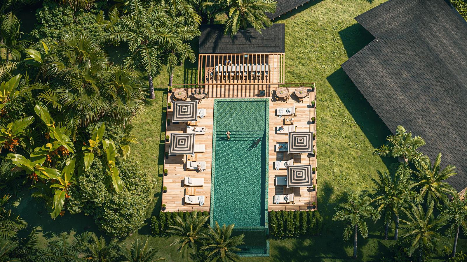 An aerial view shows a rectangular swimming pool surrounded by a wooden deck and palm trees — 225 Coral Way, Bocas Del Toro,, FL