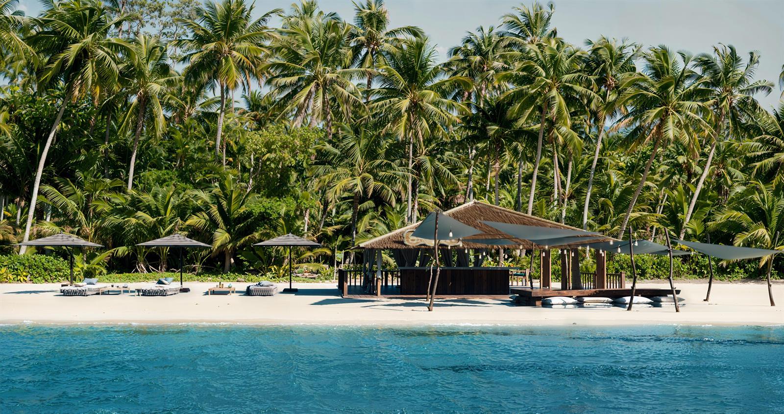 A beach bar with a thatched roof sits on a sandy shore lined with palm trees — 225 Coral Way, Bocas Del Toro,, FL