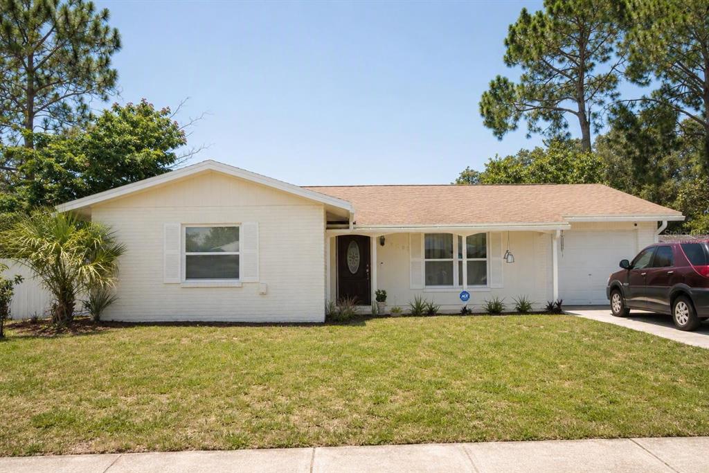 A single-story house with a white brick exterior, a brown roof, and a front driveway — 8002 WOODVINE PLACE, TAMPA, FL
