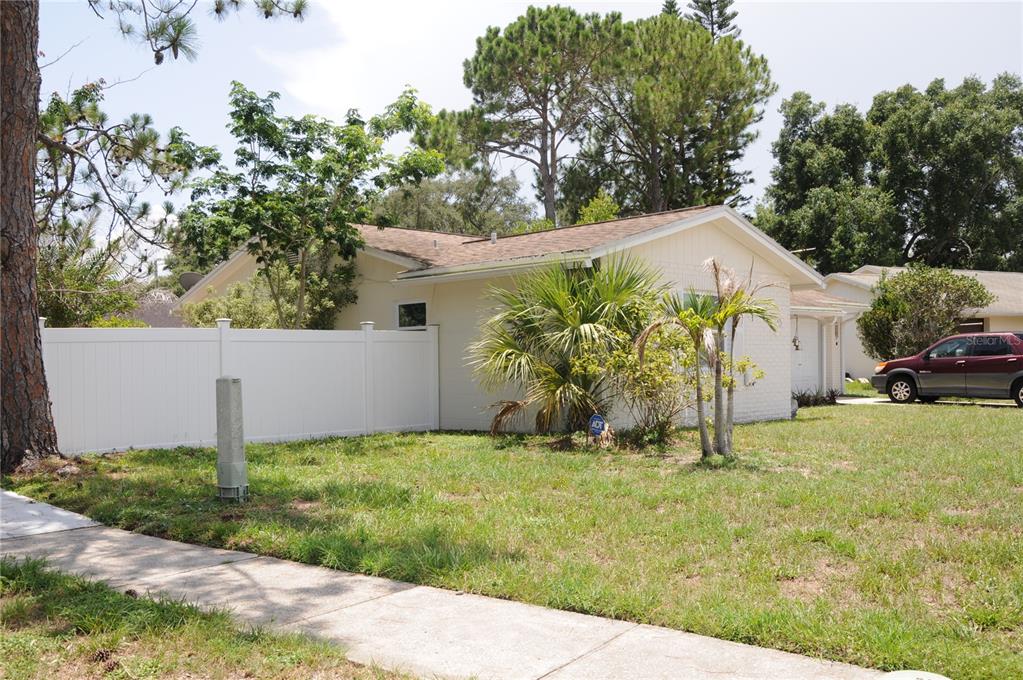 A single-story house with a white brick exterior, a white fence, and a front lawn — 8002 WOODVINE PLACE, TAMPA, FL