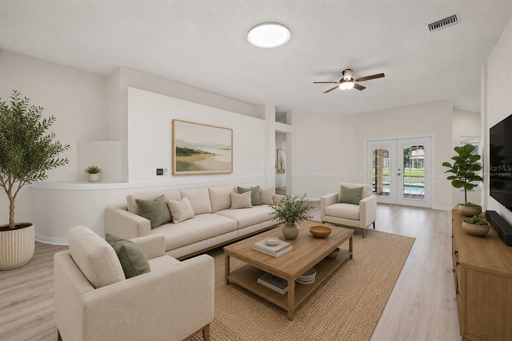A living room with a sofa, two armchairs, a coffee table, and glass patio doors — 19519 MORDEN BLUSH DRIVE, LUTZ, FL