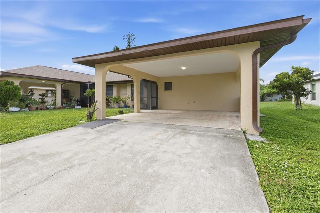 A concrete driveway leads to a covered carport attached to a single-story residential building — 10507 PENDLETON AVENUE UNIT B, ENGLEWOOD, FL