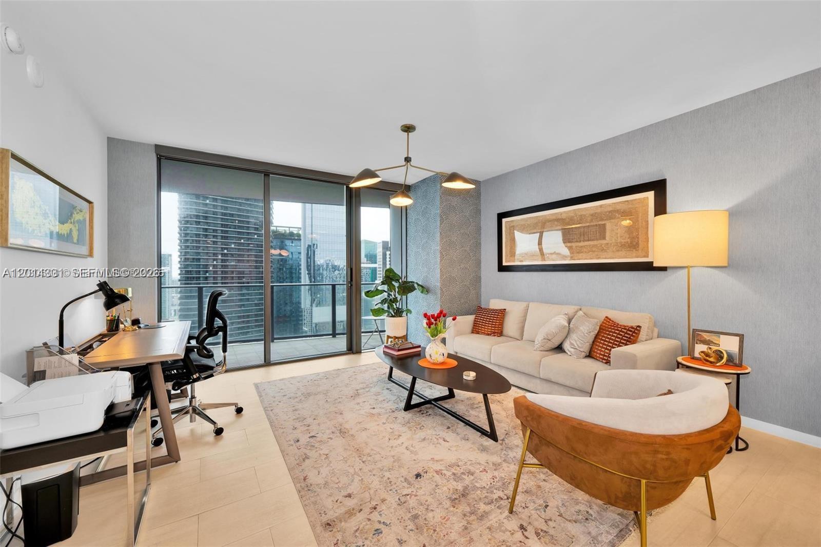 A modern living room features a desk, sofa, armchair, and a balcony with city views — 1000 Brickell Plz # 3914, Miami FL 33131, MIAMI, FL