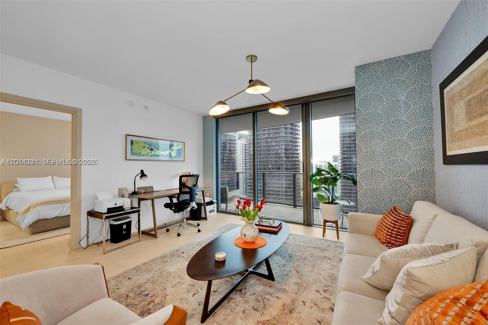 A living room with a desk area, a sofa, and a view of city skyscrapers — 1000 Brickell Plz # 3914, Miami FL 33131, MIAMI, FL