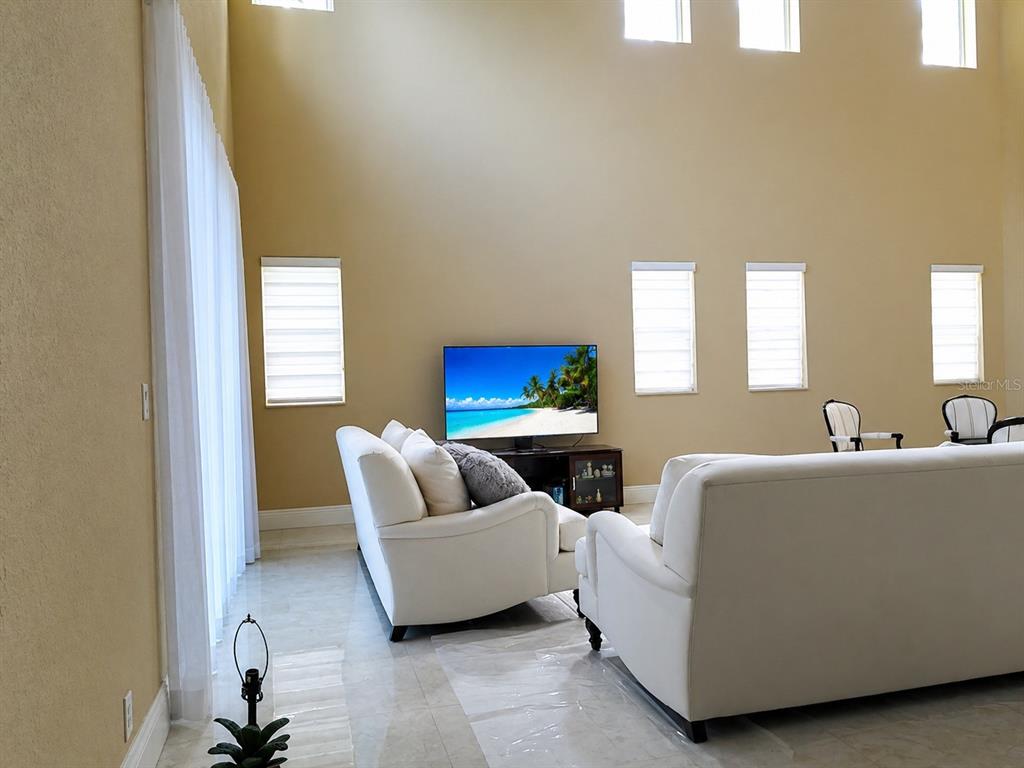 A living room with high ceilings, white sofas, and a television on a media console — 143 NW 117TH AVENUE, PLANTATION, FL