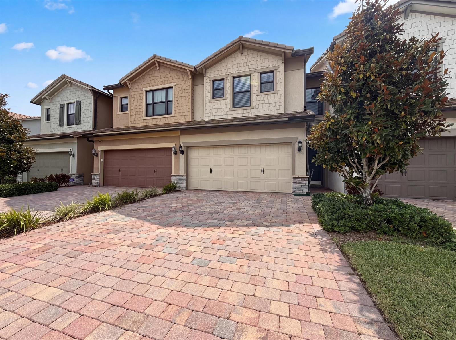 A row of two-story townhouses with paved driveways and attached garages under a blue sky — 4739 Eventing Street, Lake Worth FL 33467, LAKE WORTH, FL