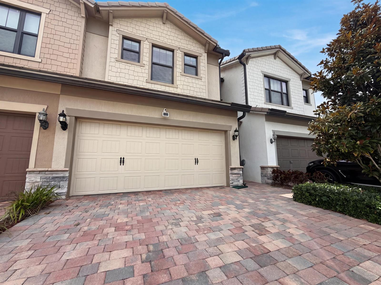 A two-story townhouse with a beige garage door and a brick paver driveway — 4739 Eventing Street, Lake Worth FL 33467, LAKE WORTH, FL